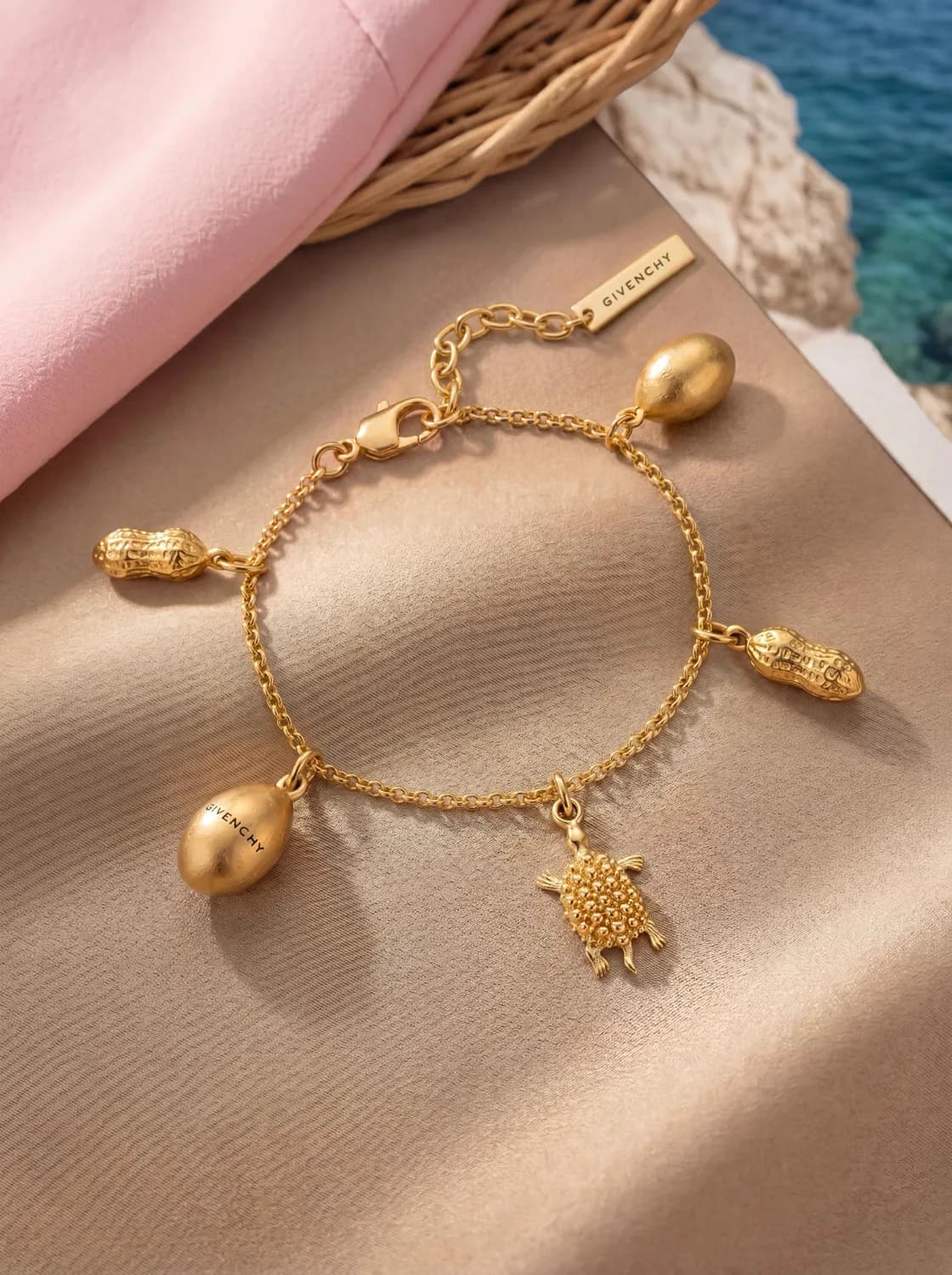 Gold charm bracelet on pink silk by the sea